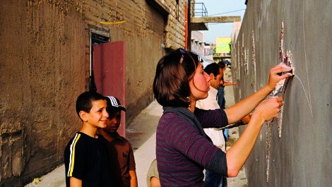 German volunteer working on the mosaic on the exterior wall.